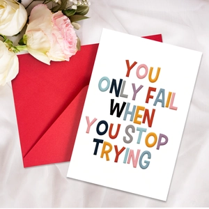 Close-up of motivational greeting card with red envelope and white rose on fabric