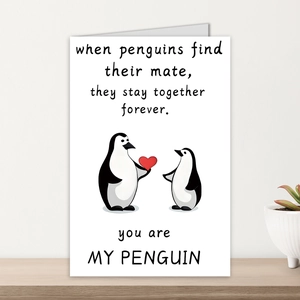 Detail of Valentine's card with cartoon penguins on a minimalist wooden surface