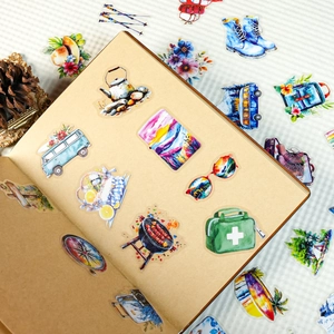 Detail of travel themed PET stickers with watercolor camping icons on a notebook