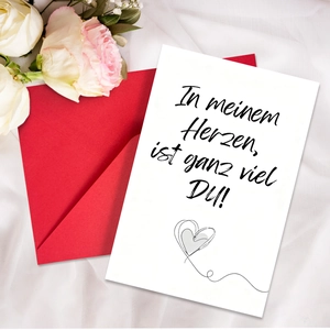 Detailaufnahme der deutschen Valentinskarte mit rotem Umschlag auf weißer Seide und Rosen