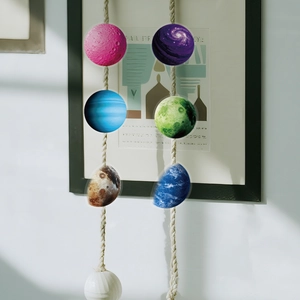 Detailed view of colorful space planet hanging ornaments on rustic ropes with textured finish