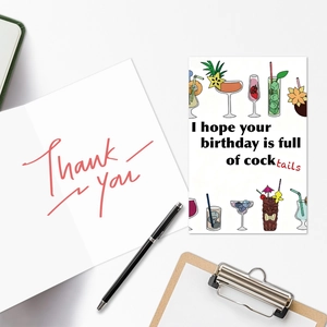 Bovenaanzicht van verjaardagskaart met cocktails en bedankkaart op een wit bureau