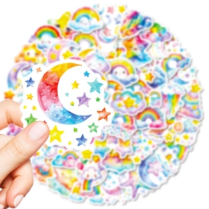 Hand holding vibrant watercolor cartoon star and rainbow stickers for DIY crafts