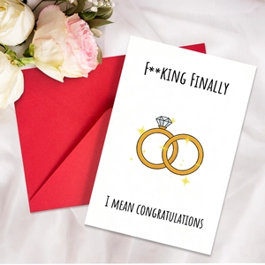 Lustige Hochzeitskarte mit goldenen Ringen und rotem Umschlag auf weißem Seidenstoff