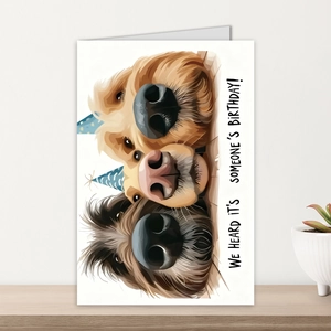 Detail shot of a large humor birthday card featuring cute dogs in party hats on wood desk