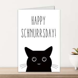 Detail of a folded greeting card with a black cat illustration on a wooden desk
