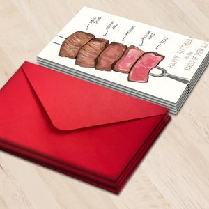 Humorous steak themed birthday card set with red envelope on a wooden background