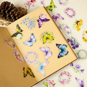 Dettaglio di adesivi traslucidi con farfalle e fiori su un taccuino stile vintage