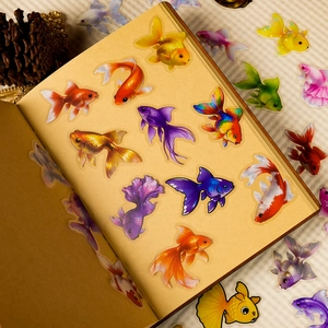 Detail view of colorful transparent PET goldfish stickers on a vintage notebook