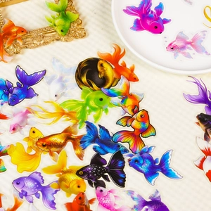 Vibrant PET goldfish stickers for scrapbooking displayed on an artistic background