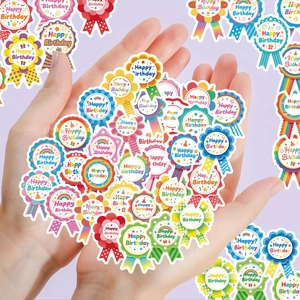 Close-up of hand holding colorful Happy Birthday badge stickers for gift decoration