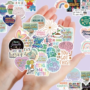 Mains tenant un lot de stickers santé mentale avec des citations inspirantes colorées