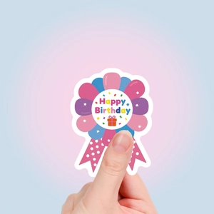 Detail of a pink Happy Birthday medal sticker with polka dot ribbons held in hand