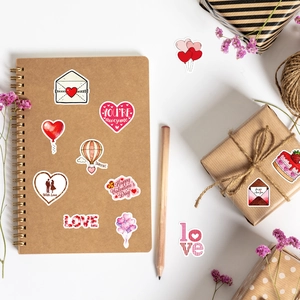 Flat lay of Valentine stickers with red hearts and roses on a craft notebook
