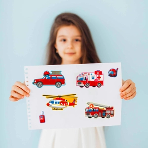 Girl holding educational cartoon vehicle stickers with fire trucks and ambulances