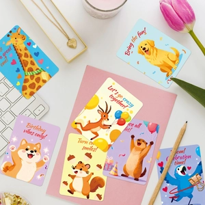 Flat lay of colorful cartoon animal birthday cards with motivational English text and props
