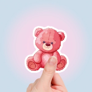 Hand holding a cute pink teddy bear cartoon sticker showing size and vibrant color detail