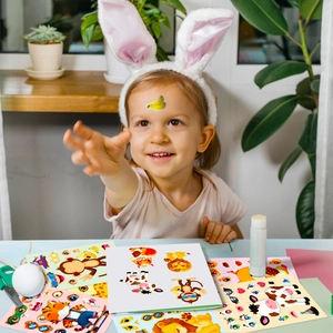 Close-up of a child playing with colorful cartoon animal face stickers for DIY crafts