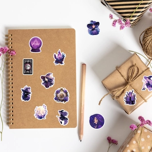 Detail of purple witch magic stickers with tarot cards and crystals on a notebook