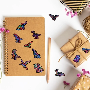 Neon dinosaur stickers shown as creative decorations on a craft notebook and gift boxes