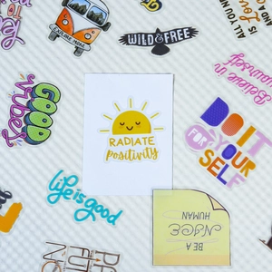 Close-up of waterproof transparent PET stickers with positive motivational quotes on white grid