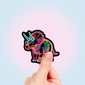 Neon style triceratops sticker with vibrant colorful dinosaur skeleton design held by hand