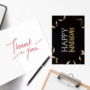 Neon style birthday and thank you greeting cards with envelopes and pen on desk