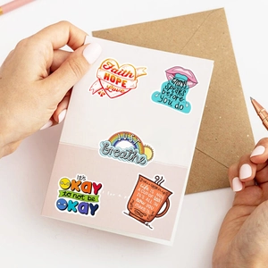 Close-up of motivational quote stickers on white card with pen and envelope