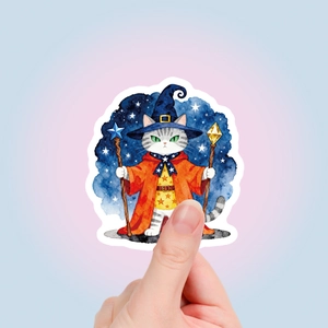 Close-up of a watercolor wizard cat sticker with a blue star hat and a magic wand