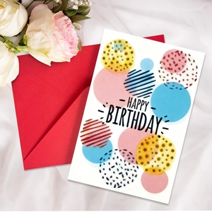 Flat lay of Happy Birthday neon card with red envelope on white textured fabric backdrop