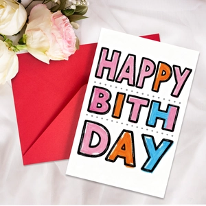 Artistic Happy Birthday card and vibrant red envelope set on white fabric
