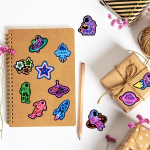 Neon astronaut stickers applied on notebook and gift box with cozy lifestyle decor
