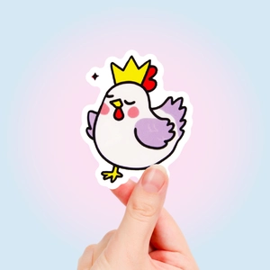 Hand holding a cute cartoon chicken sticker with crown and purple wings for decoration