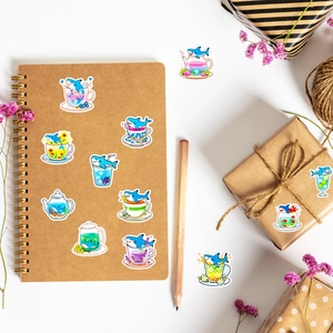 Detail of cute shark tea cup stickers on a desk with a notebook and gift box