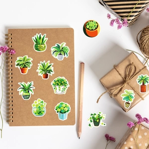Close-up of green potted plant stickers on a notebook with decorative office props