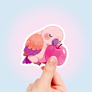 Close-up of cute cartoon parrot sticker with hand showing size for scrapbooking