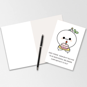 Macro shot of a folded birthday card with a funny sprout illustration and matching pen