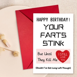 Close-up of humor birthday card with red heart and matching red envelope on linen