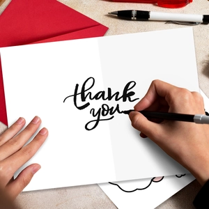 Detail of Thank You card with red envelope and pen on a textured background