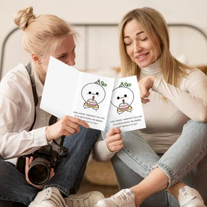 Women holding funny birthday card with cartoon character and humorous English text