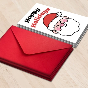 Close-up of Christmas card set with Santa Claus design and red envelopes on wood