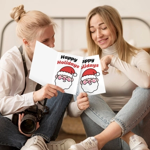 Two women sharing Santa Claus Christmas cards on a bedroom floor in a cozy setting