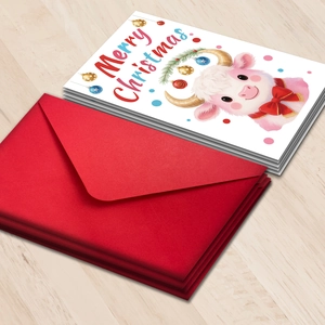 Close-up of cute cartoon calf Christmas card set with red envelopes on wooden background