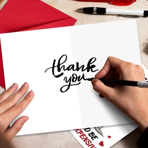 Primer plano de escritura en tarjeta de agradecimiento con sobre rojo elegante