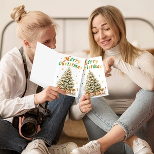 Gros plan d'une carte de Noël aquarelle tenue à la main dans un décor chaleureux