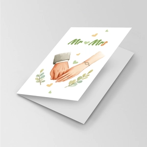 Close-up of Mr and Mrs wedding card with minimalist hand-drawn illustration and green leaves