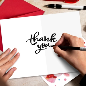 Macro detail of thank you card with red envelope and handwriting pen in use scene