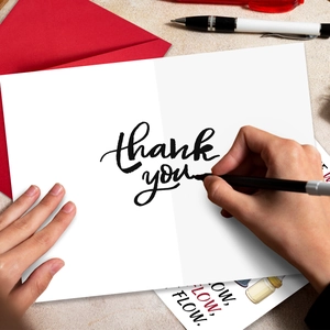 Close-up of a white greeting card with handwritten thank you text and a red envelope