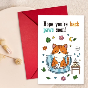 Detail view of cartoon cat recovery card and red envelope on a rustic fabric background