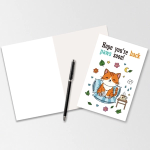Close-up of get well card with cartoon cat and text Hope you are back paws soon
